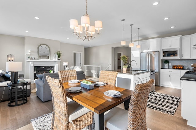 dining space with light wood-type flooring, an inviting chandelier, and sink