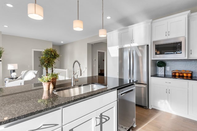 kitchen with pendant lighting, white cabinets, appliances with stainless steel finishes, and sink