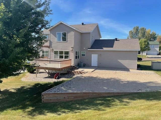 back of house featuring a deck, a lawn, and central air condition unit