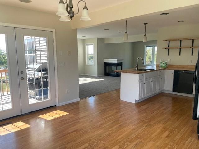 kitchen featuring sink, dishwasher, white cabinetry, decorative light fixtures, and french doors