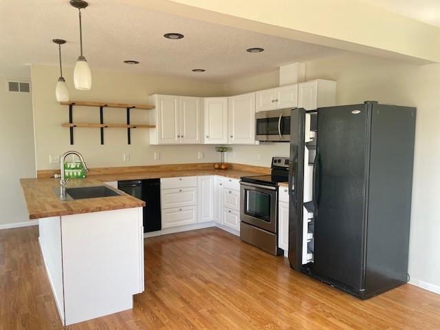 kitchen featuring pendant lighting, sink, white cabinetry, black appliances, and kitchen peninsula