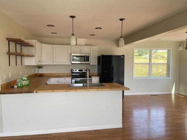 kitchen with hanging light fixtures, stainless steel appliances, kitchen peninsula, and white cabinets