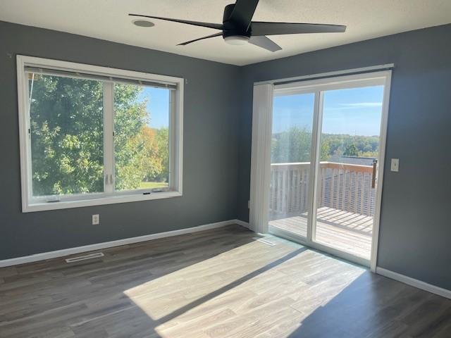 empty room with ceiling fan, dark hardwood / wood-style flooring, and a wealth of natural light