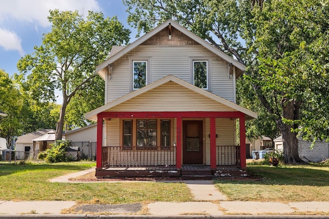 view of front facade with a front yard, covered porch, and fence