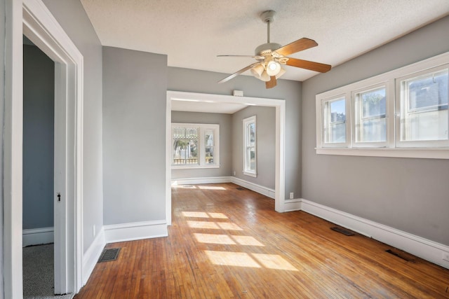 spare room with visible vents, a textured ceiling, baseboards, and hardwood / wood-style flooring