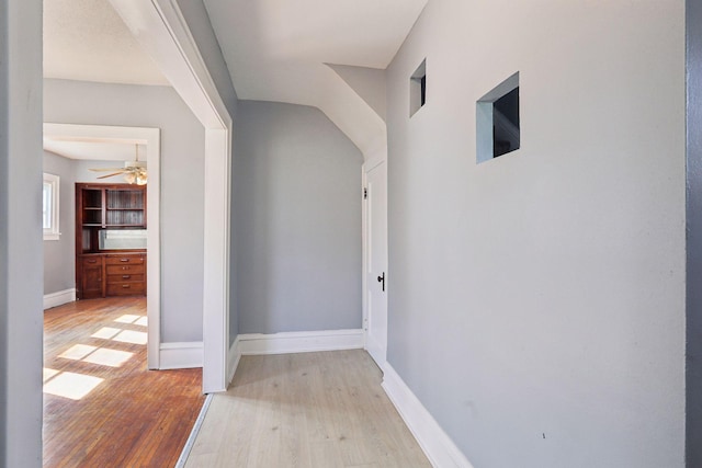 corridor with baseboards and light wood-style floors