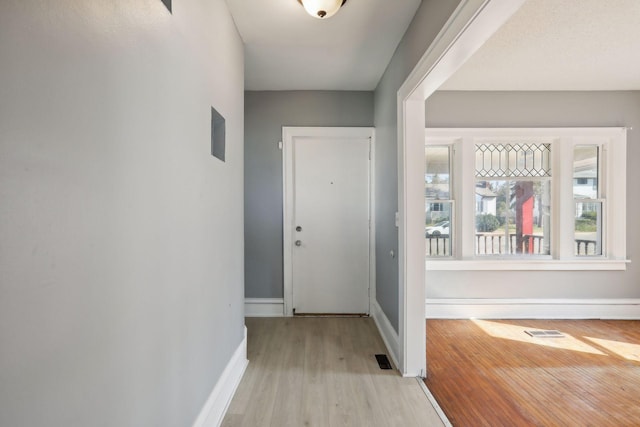 foyer entrance featuring visible vents, light wood-style flooring, and baseboards