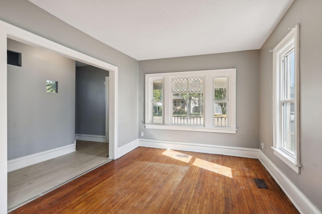 unfurnished room with hardwood / wood-style flooring, baseboards, and visible vents