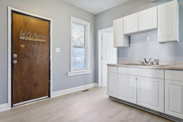 kitchen with light wood-style flooring, visible vents, white cabinetry, baseboards, and light countertops