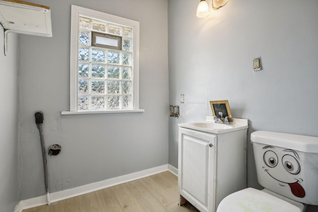 half bathroom featuring vanity, wood finished floors, toilet, and baseboards