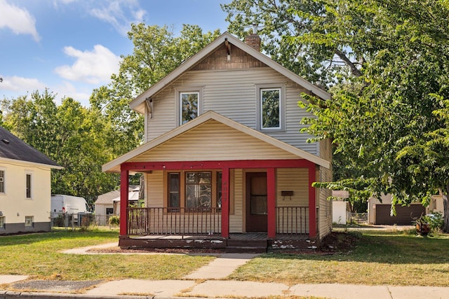 view of front of house featuring covered porch, fence, a chimney, and a front lawn