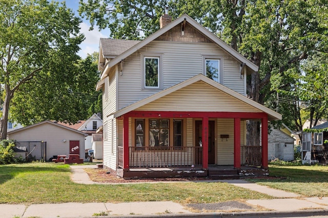 view of front of house featuring a porch, a front yard, and a chimney