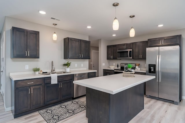 kitchen with hanging light fixtures, appliances with stainless steel finishes, light hardwood / wood-style flooring, dark brown cabinetry, and sink