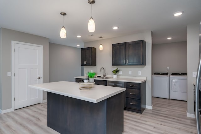 kitchen with washer and clothes dryer, dark brown cabinets, sink, a center island, and light hardwood / wood-style floors