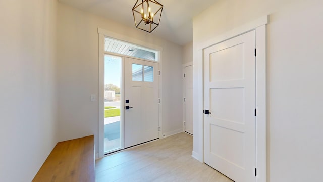 foyer with light wood-type flooring, a healthy amount of sunlight, and a notable chandelier