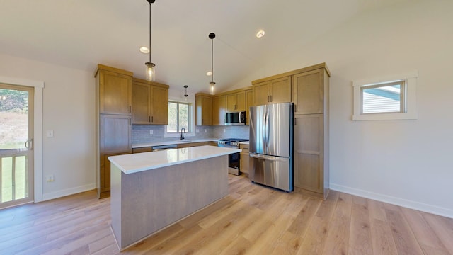 kitchen with pendant lighting, a kitchen island, backsplash, appliances with stainless steel finishes, and light hardwood / wood-style floors