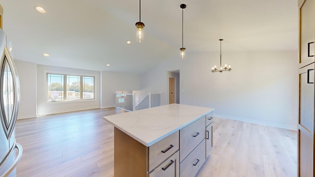 kitchen featuring stainless steel fridge, a kitchen island, a chandelier, light wood-type flooring, and vaulted ceiling