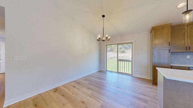 unfurnished dining area with light hardwood / wood-style floors, vaulted ceiling, and a chandelier