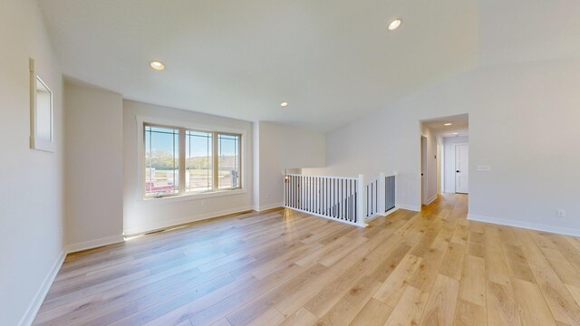 unfurnished room with light hardwood / wood-style flooring and lofted ceiling