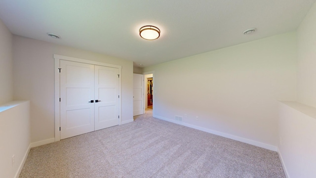 unfurnished bedroom with a closet and light colored carpet