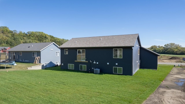 back of property featuring a trampoline, central air condition unit, and a yard