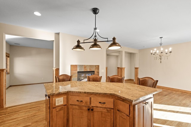 kitchen with a kitchen island, light hardwood / wood-style flooring, a tile fireplace, and a breakfast bar