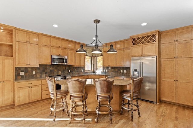 kitchen featuring a kitchen island, light hardwood / wood-style floors, stainless steel appliances, pendant lighting, and a breakfast bar