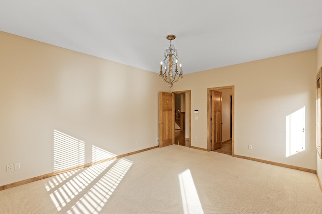 carpeted spare room featuring an inviting chandelier