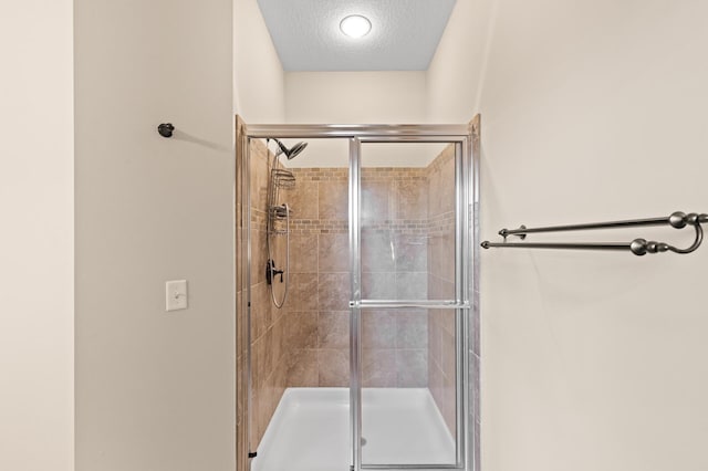 bathroom with a shower with door and a textured ceiling