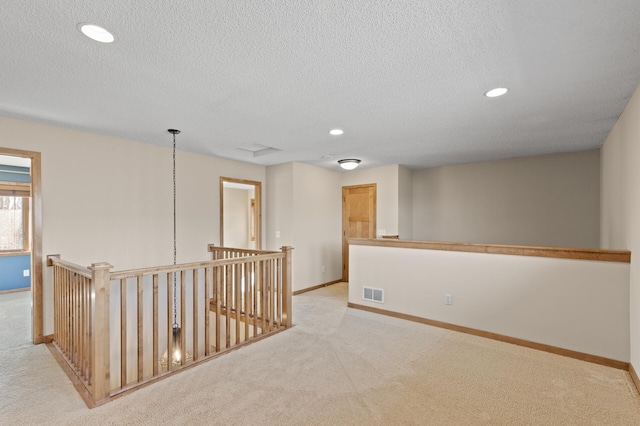 corridor featuring light carpet and a textured ceiling