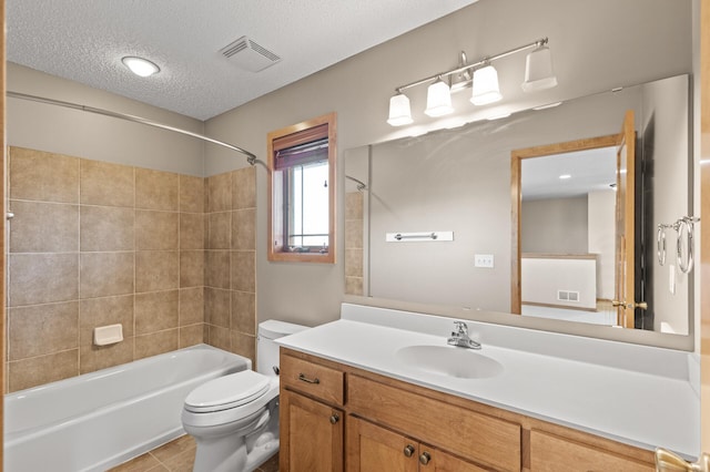 full bathroom featuring a textured ceiling, toilet, tiled shower / bath, vanity, and tile patterned flooring