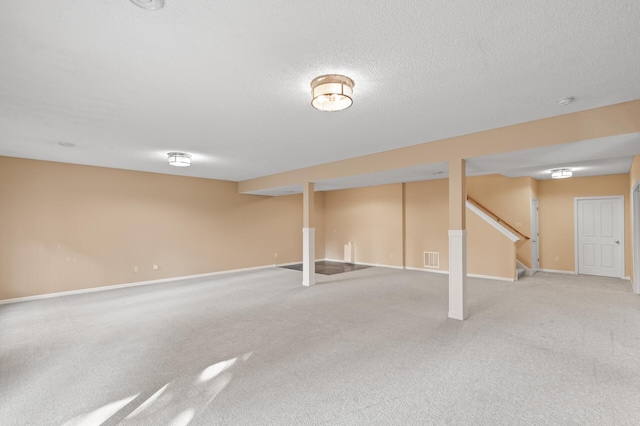 basement featuring light carpet and a textured ceiling