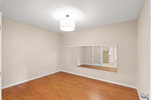 spare room featuring hardwood / wood-style floors and a textured ceiling