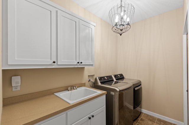 clothes washing area with dark tile patterned floors, sink, a notable chandelier, cabinets, and washing machine and clothes dryer