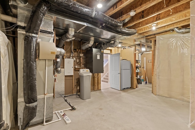 basement featuring heating unit and white refrigerator