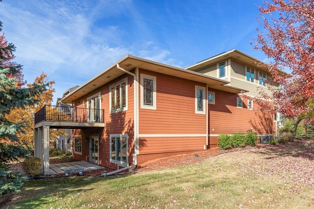 view of property exterior featuring a yard, a deck, and a patio