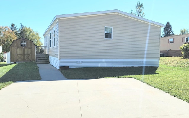 view of side of home featuring a lawn, central air condition unit, and a shed