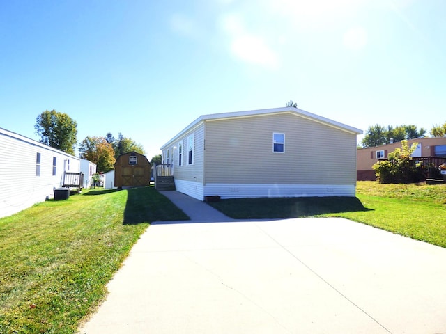 view of side of home featuring an outbuilding, concrete driveway, a yard, and a shed