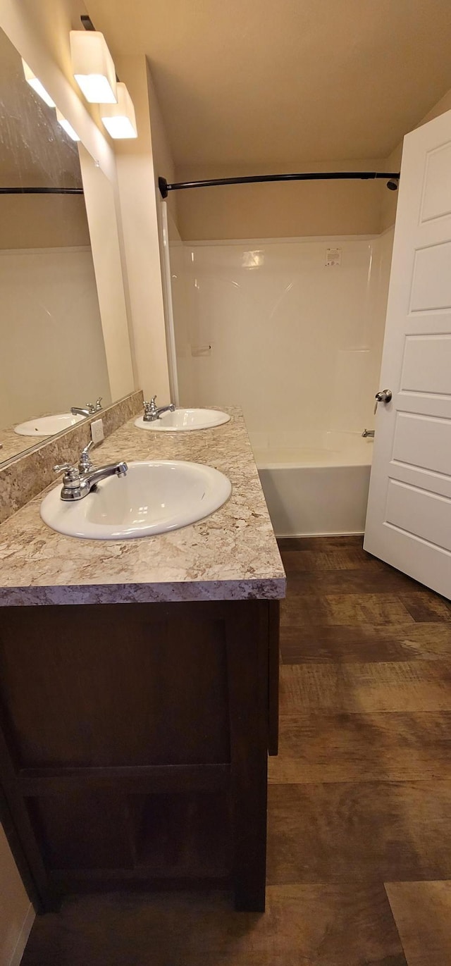 full bath with washtub / shower combination, wood finished floors, a sink, and double vanity