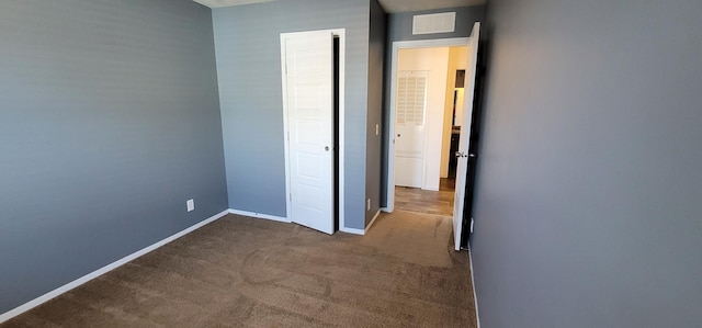 unfurnished bedroom with carpet, visible vents, and baseboards