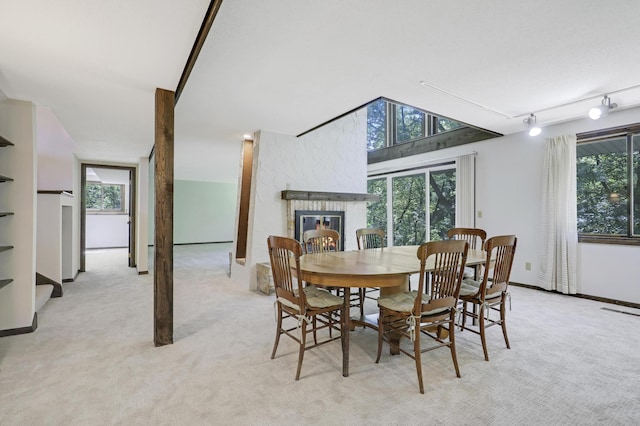 carpeted dining area with a wealth of natural light, track lighting, and a fireplace