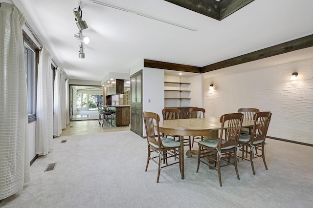 carpeted dining space featuring track lighting