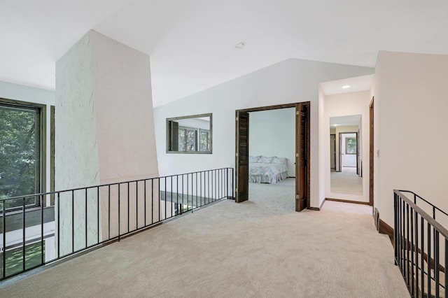 hallway with light carpet and lofted ceiling