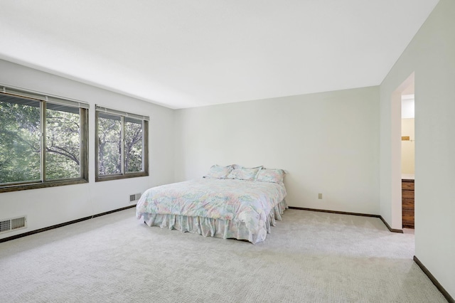 bedroom with light carpet and ensuite bath