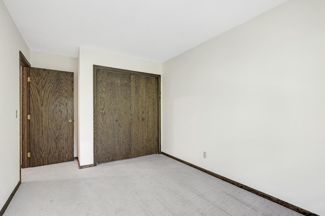 unfurnished bedroom with light carpet and a closet