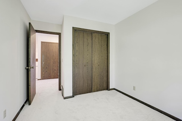 unfurnished bedroom with light carpet and a closet