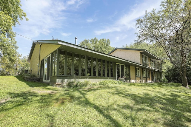 rear view of property with a lawn and a sunroom