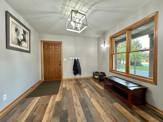 entrance foyer featuring hardwood / wood-style floors, a textured ceiling, and a notable chandelier