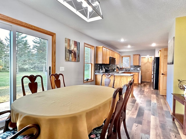 dining area with a textured ceiling, sink, and light hardwood / wood-style flooring