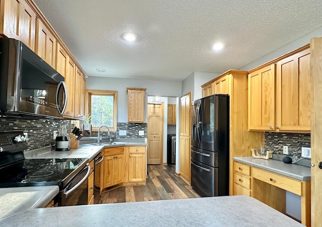 kitchen with hardwood / wood-style floors, backsplash, stainless steel appliances, and sink